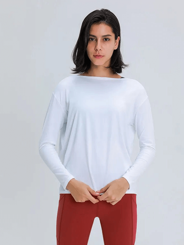 Woman wearing a long-sleeve white top for gym, made from durable, quick-drying nylon and spandex, ideal for workouts.