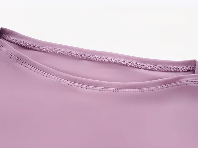 Close-up of a solid color gym top neckline in pink, featuring durable nylon-spandex blend and breathable, quick-drying fabric.