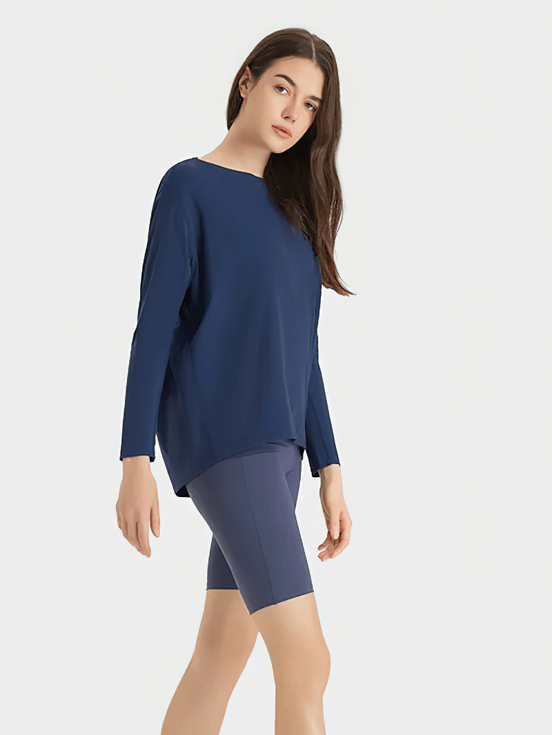 Woman wearing a navy blue long sleeve loose top for gym made of nylon and spandex, showcasing breathable and quick-dry features.