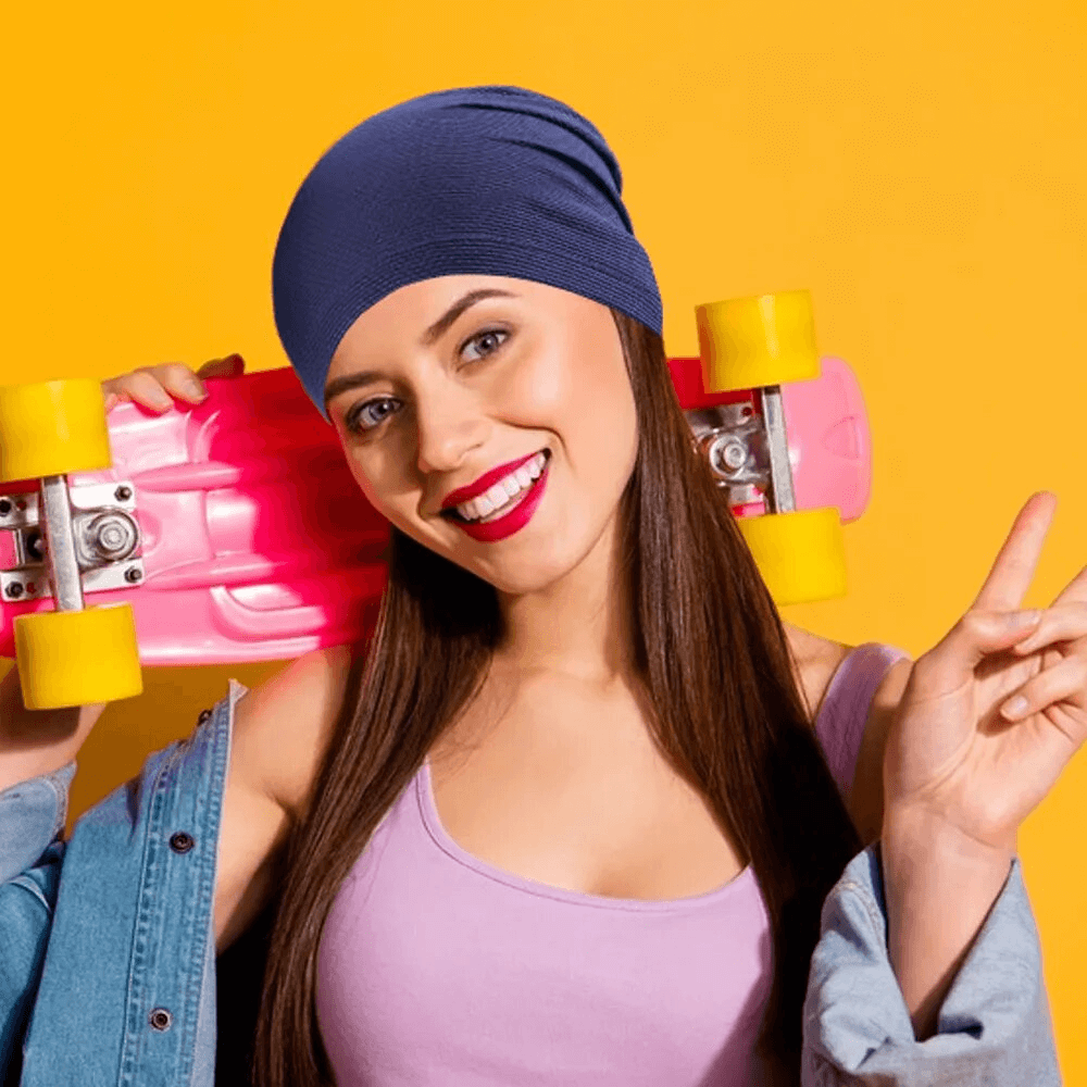 Unisex fashion beanie in blue for outdoor sports, worn by a smiling skater with a pink skateboard.
