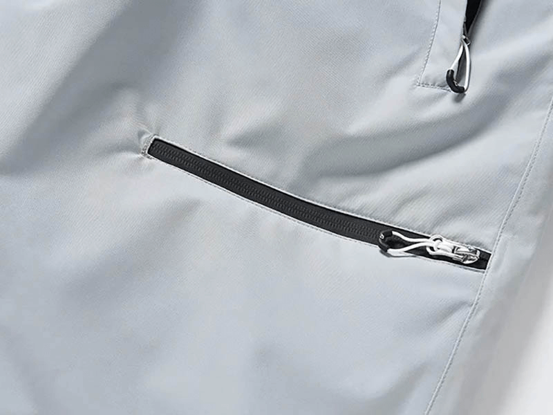 Close-up of zipper fly pocket on waterproof snowboarding pants, showcasing windproof polyester material and sleek design.