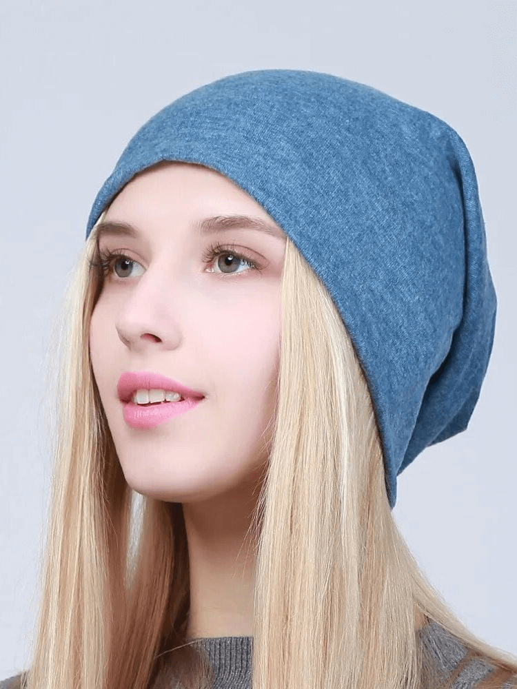 Woman wearing a blue cotton casual beanie, fashionable and multifunctional for casual wear. Solid pattern, perfect for added warmth and style.