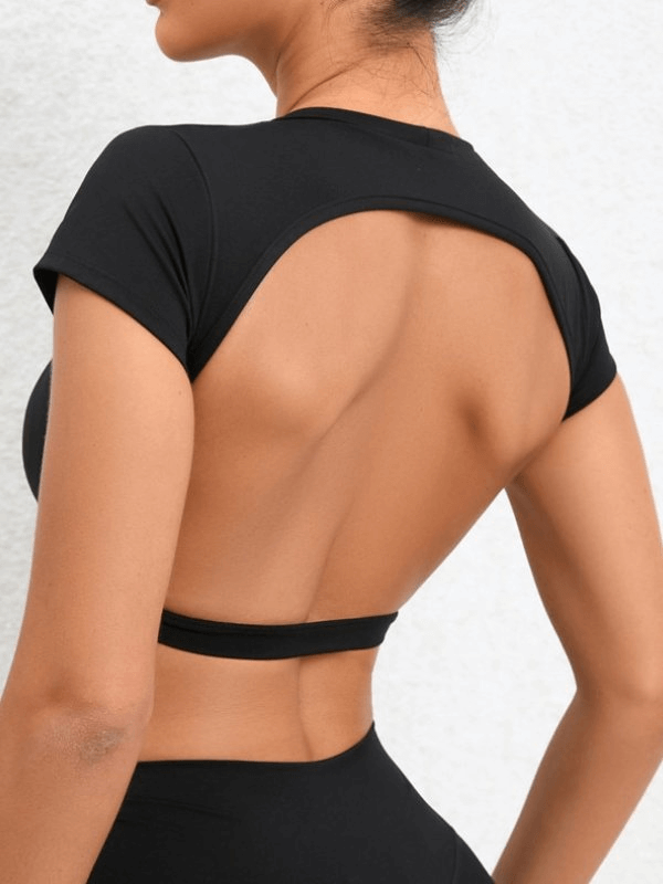 Woman wearing black fashionable elastic cropped open back yoga top SF1370, short-sleeve, nylon material.