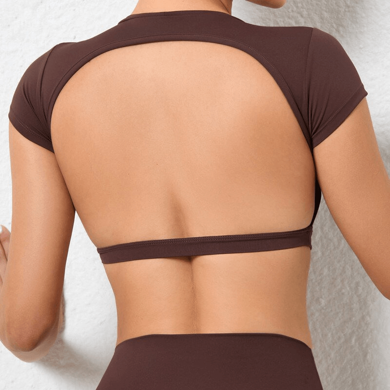 Women's elastic cropped open back top in nylon, perfect for yoga. Stylish and breathable short sleeve in brown. Model showing back detail.