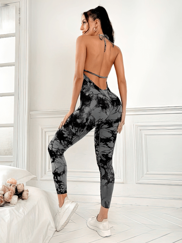 Woman wearing fashionable elastic sports jumpsuit with open back and tie-dye print, perfect for yoga and fitness activities.