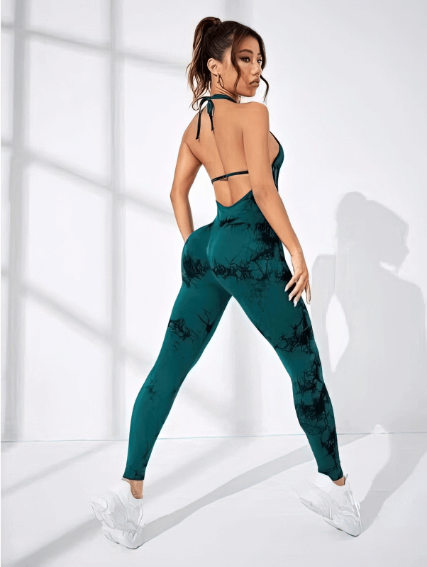 Woman wearing fashionable elastic sports jumpsuit, open back design, perfect for yoga, breathable nylon, in a stylish indoor setting.