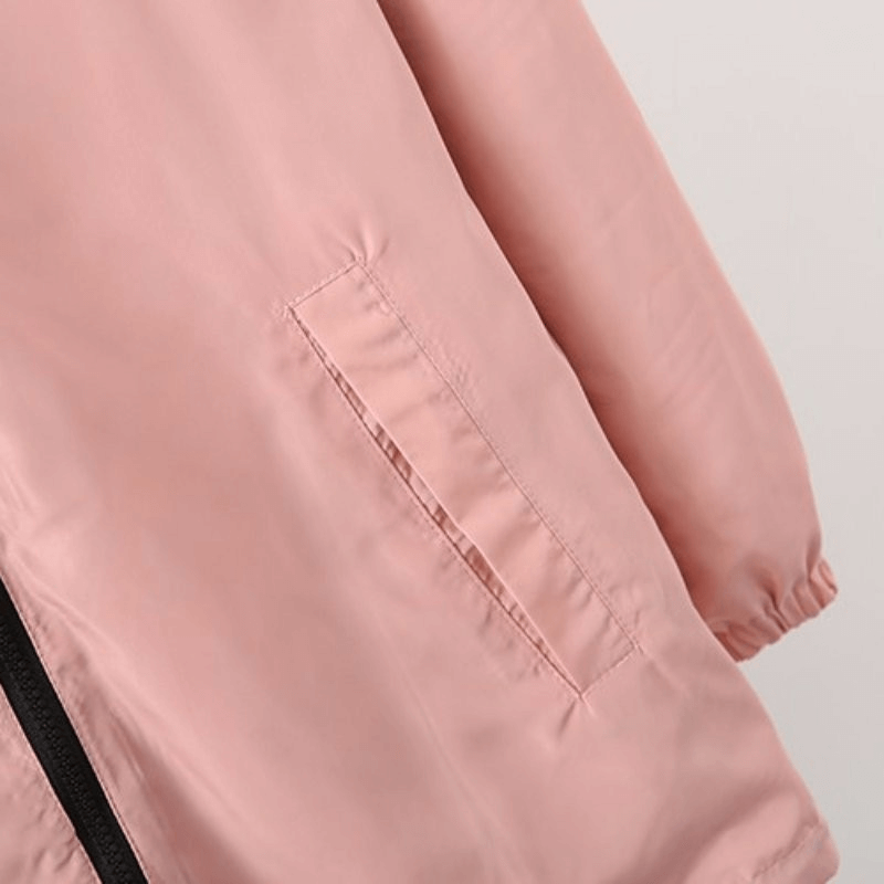 Close-up of pink two-sided breathable women's windbreaker with pocket detail, featuring cozy hood and stylish design.