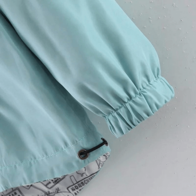 Close-up of aqua blue two-sided women's windbreaker sleeve and drawstring hem, featuring breathable fabric and stylish design details.