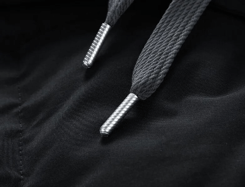 Close-up of drawstrings on a fashionable warm unisex hooded down jacket, highlighting durable metal tips and textured fabric.