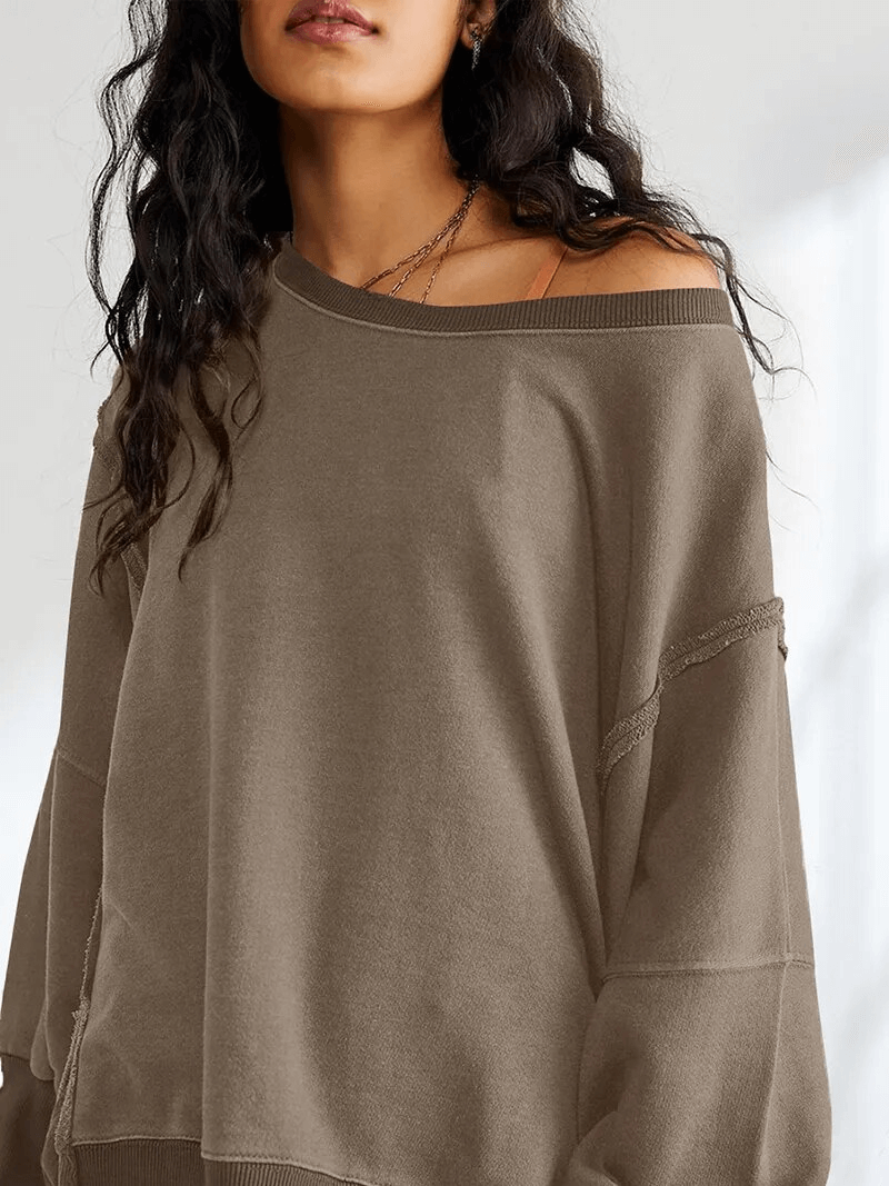 Woman wearing a stylish oversized sweatshirt with reversible seam, showcasing O-neck collar and full sleeves in a comfy, cotton fabric.