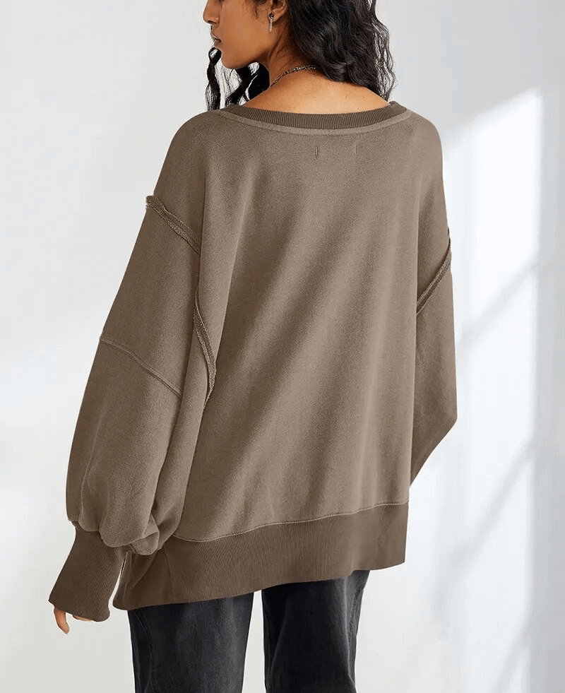 Woman wearing brown oversize sweatshirt with reversible seam and O-neck collar, showcasing a relaxed fit and full sleeves.