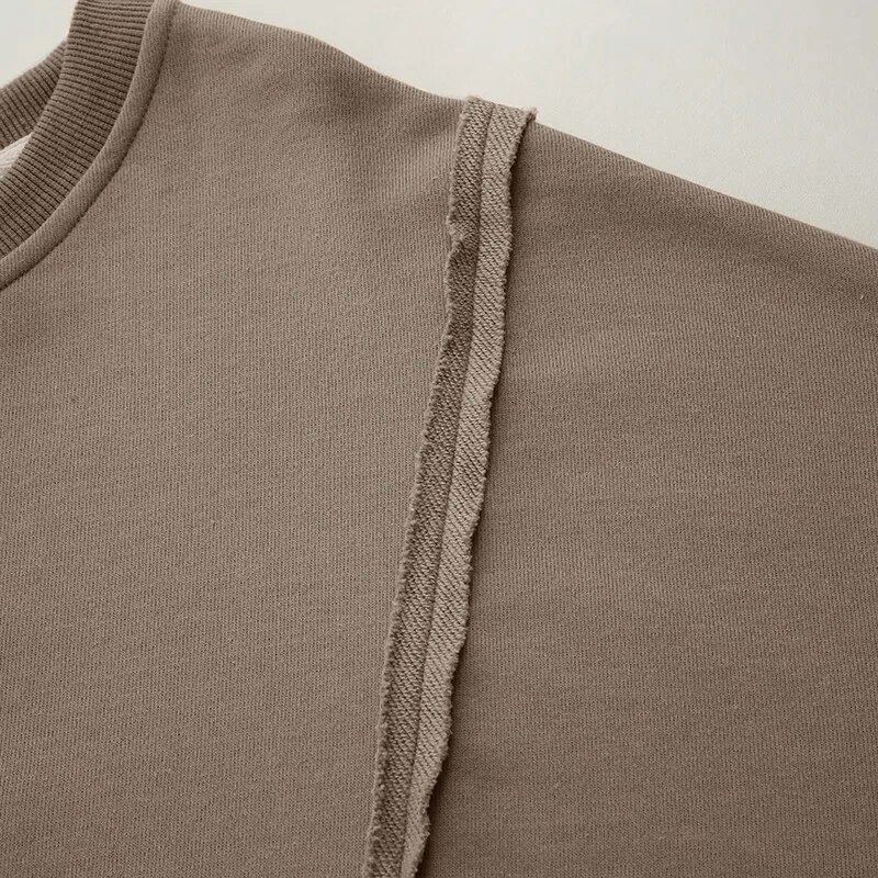 Close-up of women's oversize sweatshirt with reversible seam and O-neck collar, showcasing the patchwork detail on the sleeve.