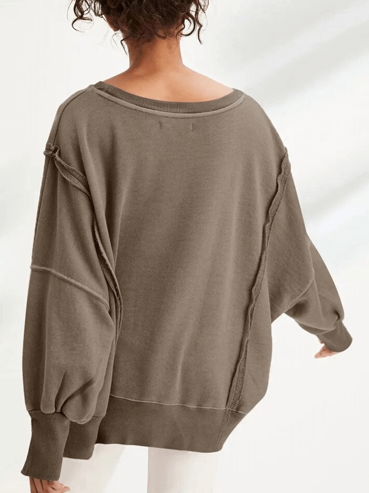Woman wearing fashionable oversized sweatshirt with reversible seam and O-neck collar.