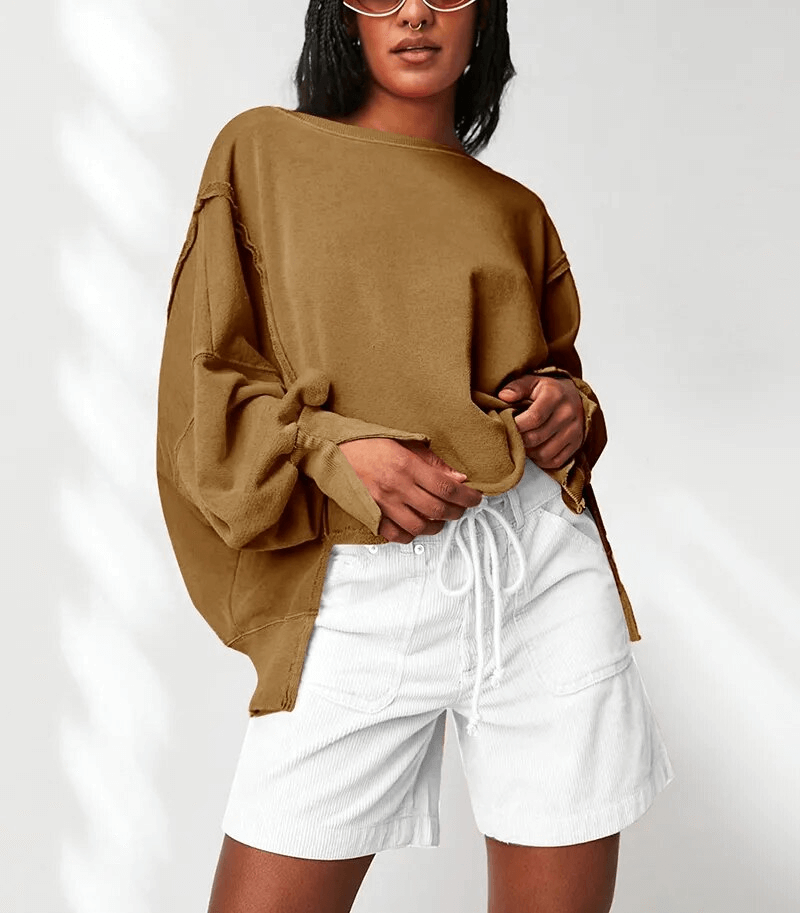 Chic oversized women's sweatshirt with reversible seam and O-neck, styled with white shorts for a trendy casual look.