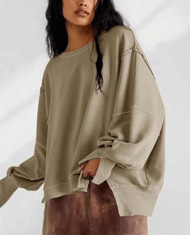 Woman wearing fashionable oversize sweatshirt with reversible seam and O-neck collar, showcasing loose fit and patchwork design.