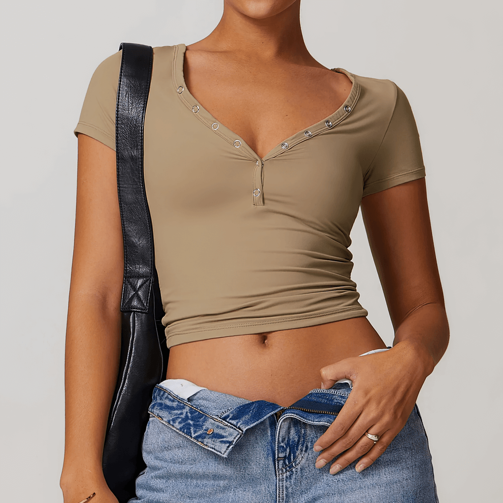 Tan V-neck button short sleeve yoga T-shirt for women, stylish and functional activewear, paired with denim jeans and black bag.