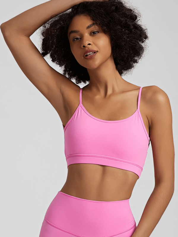 Woman wearing pink solid color open back sports bra, activewear, SF1488, showcasing breathable nylon spandex design, perfect for workouts.