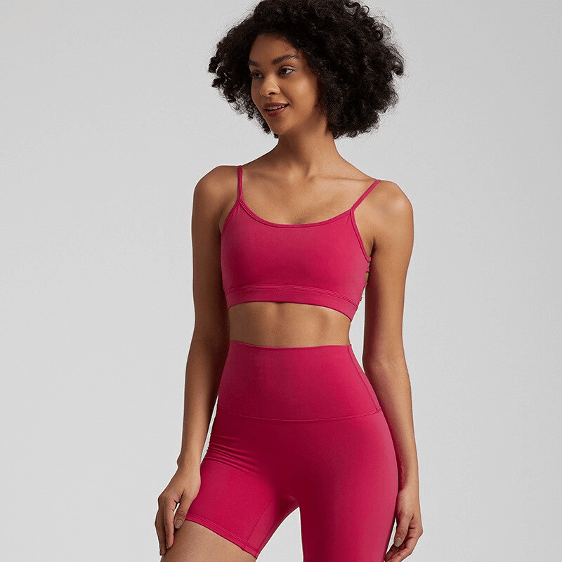 Woman wearing red open-back sports bra and high-waisted shorts, perfect for workouts, made from quick-dry nylon and spandex blend.