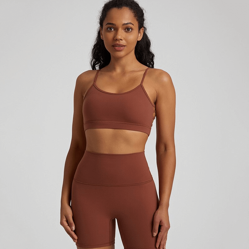 Woman wearing brown solid color open back sports bra and matching shorts, perfect for activewear and workouts.