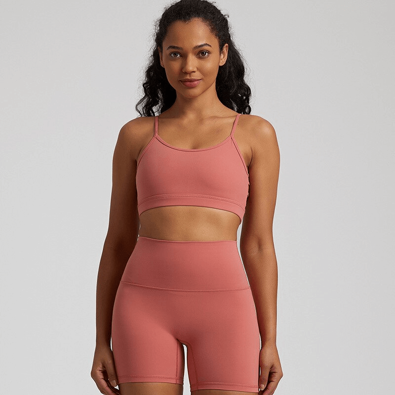 Female solid color open back sports bra and shorts set, breathable nylon-spandex blend, designed for active wear and workout comfort.
