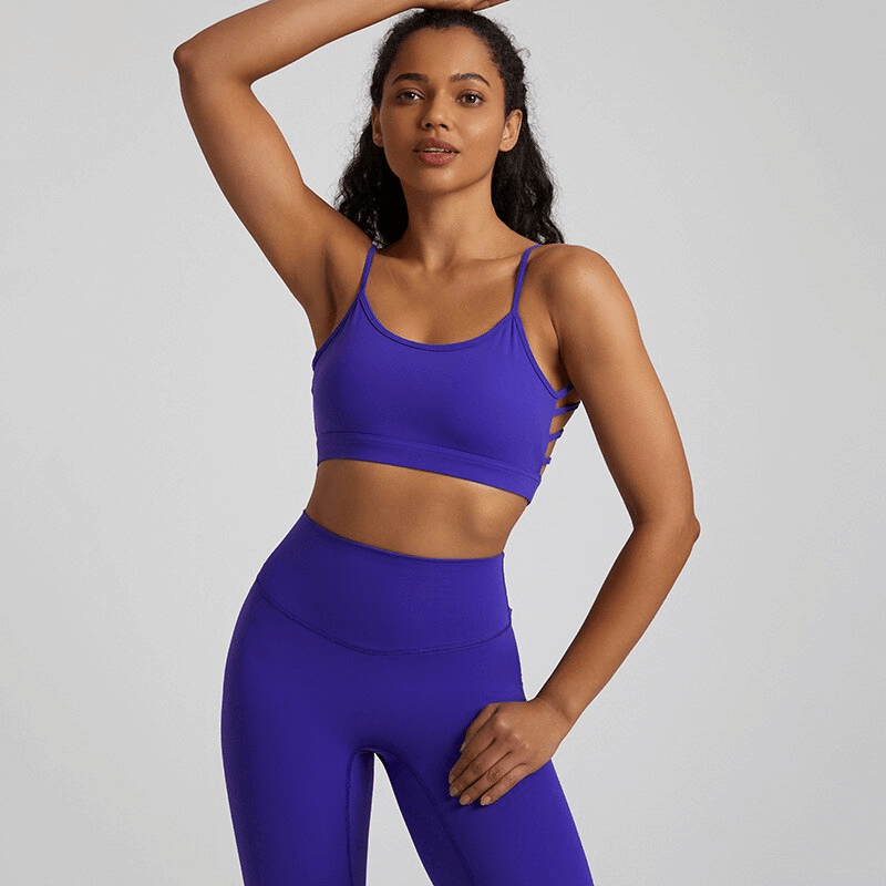 Woman wearing solid purple open back sports bra activewear, perfect for workouts, made with breathable nylon and spandex blend.
