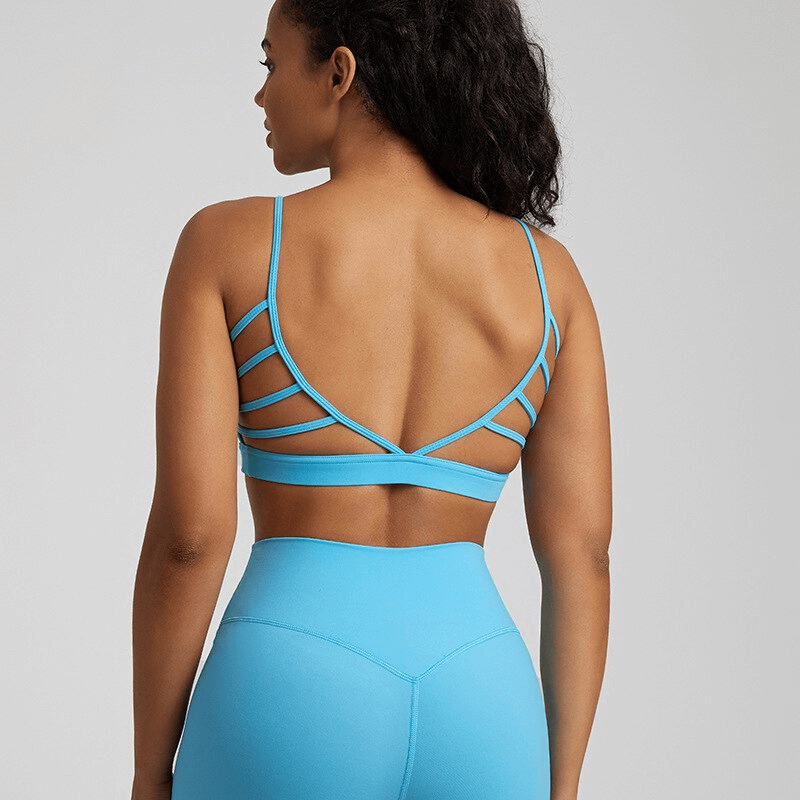 Woman wearing a blue open-back sports bra, showcasing breathable and stretchy design ideal for activewear, made of nylon and spandex.