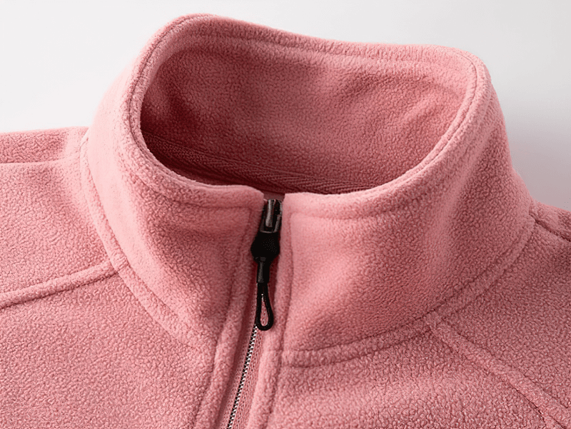 Close-up of pink stand collar zip-up fleece jacket with pockets for women, showcasing cozy fabric and stylish design.