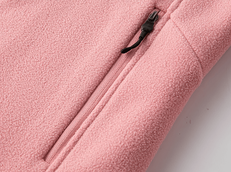 Close-up of pink fleece jacket showing zip pocket detail, emphasizing soft texture and secure storage feature.