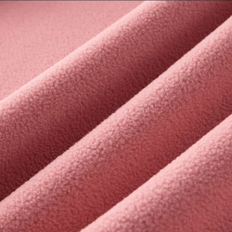Close-up of soft pink fleece fabric from a stand collar zip-up jacket, highlighting texture and warmth.