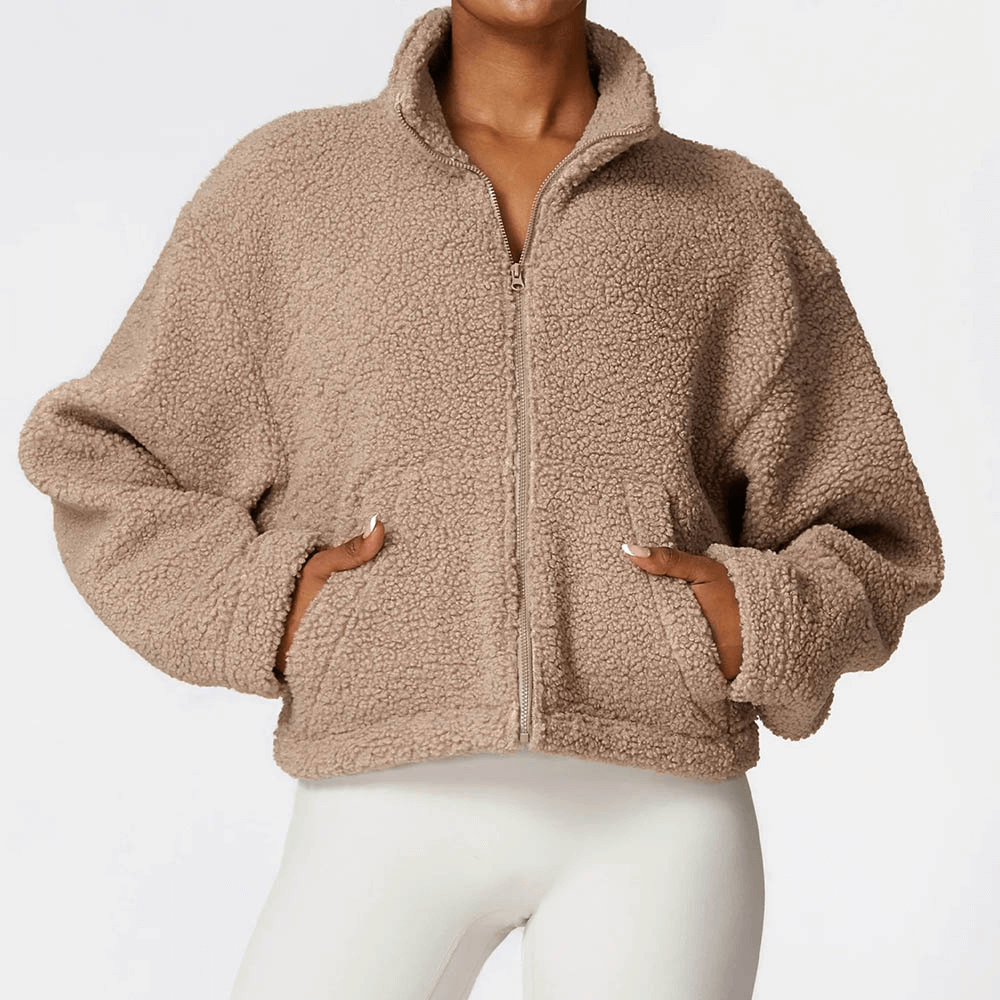 Female model wearing a thick warm fleece jacket with zipper, ideal for winter. Solid pattern in beige, crafted from breathable polyester.