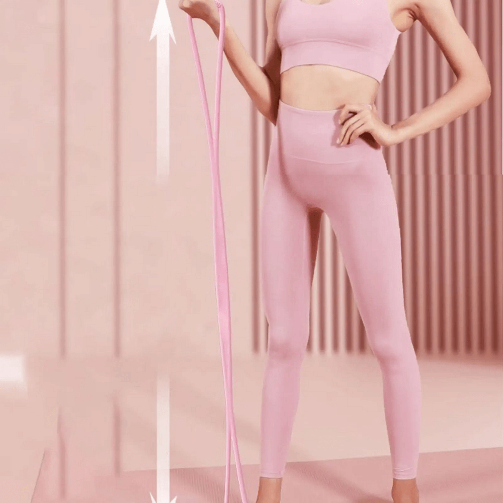 Woman using figure 8 silicone resistance bands in pink activewear, enhancing arm, back, and shoulder strength at home gym workout.