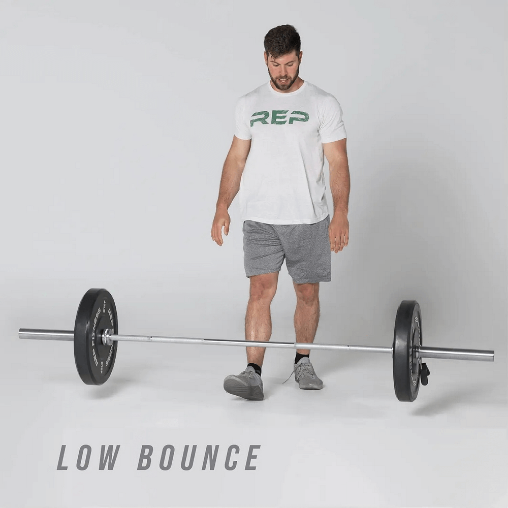 Man with barbell and REP Fitness bumper plates showcasing low bounce feature for weightlifting and strength training.
