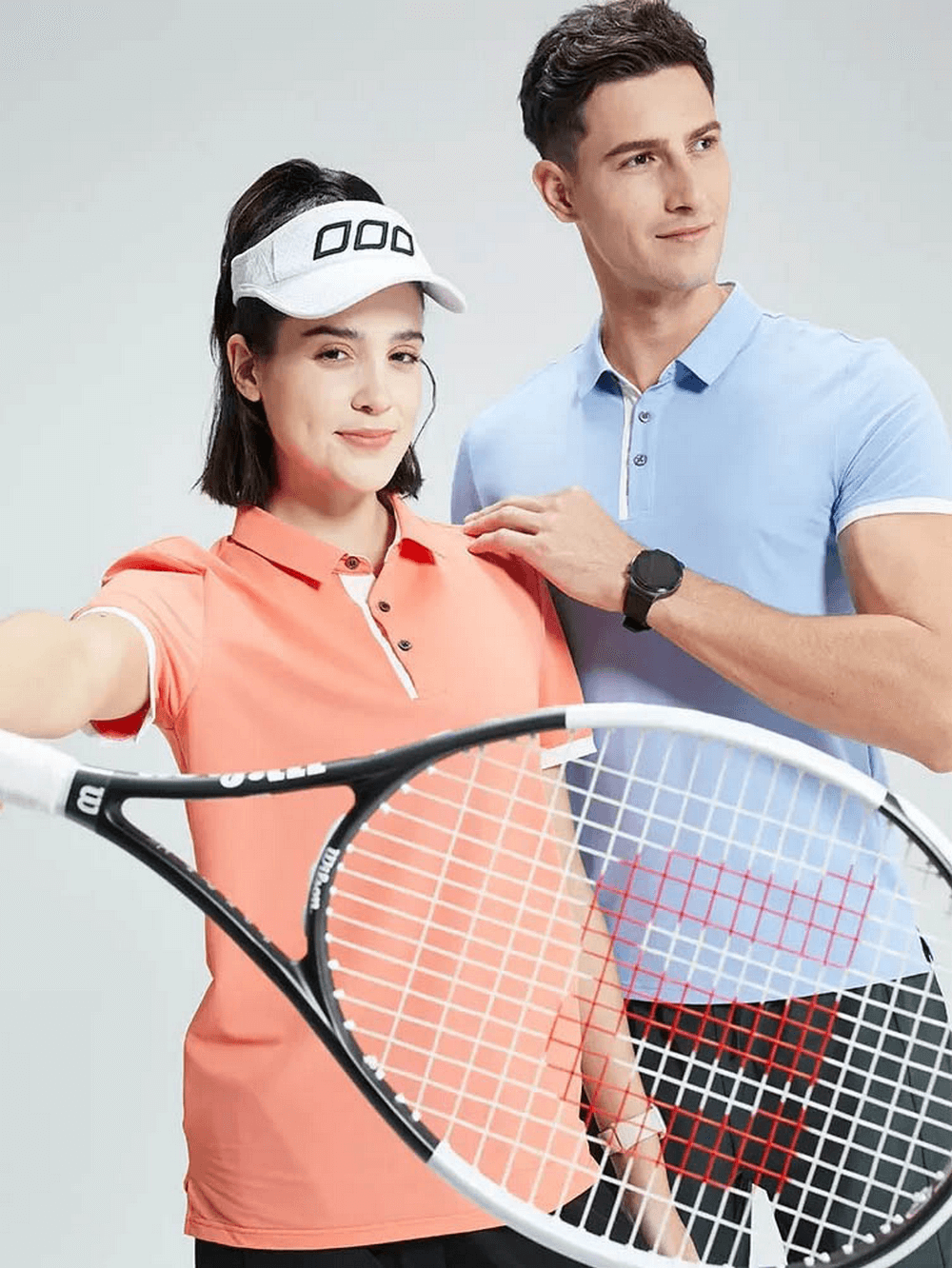 Two people wearing stylish polo shirts holding a tennis racket, showcasing a casual and sporty look.