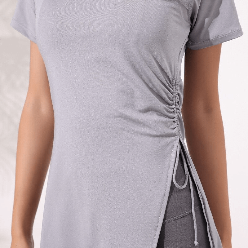 Woman wearing a fitness long t-shirt with drawstring on side, perfect for yoga. Lightweight, breathable, quick-dry material.