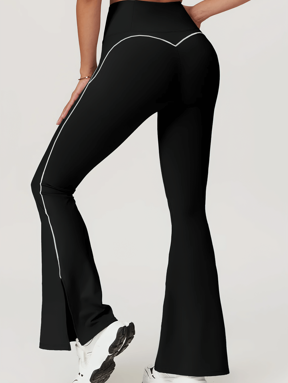 Woman wearing black flared high-waist bell-bottom fitness yoga pants with side slits, showcasing sleek and stylish athletic wear.