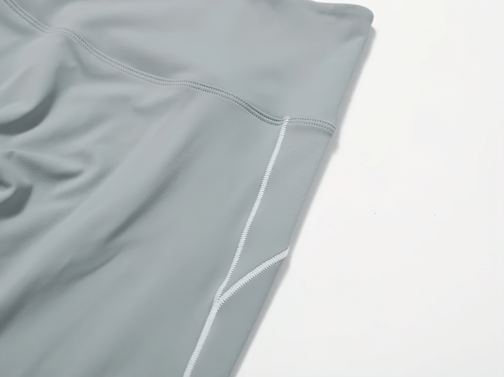 Close-up of gray flared high-waist yoga pants with side slit detail, showcasing fabric texture and stitching.