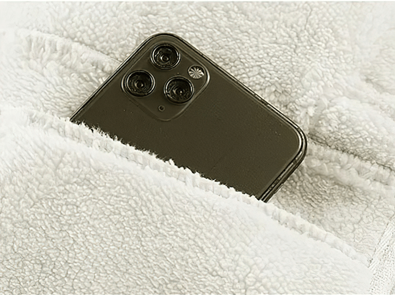 Smartphone peeking out of a cozy fleece zip-up jacket pocket, showcasing style and convenience for modern men.
