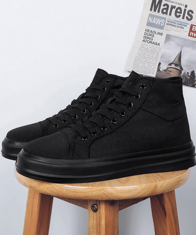 Black flexible high sports sneakers unisex with laces, showcased on a wooden stool. Perfect for comfort and everyday wear.