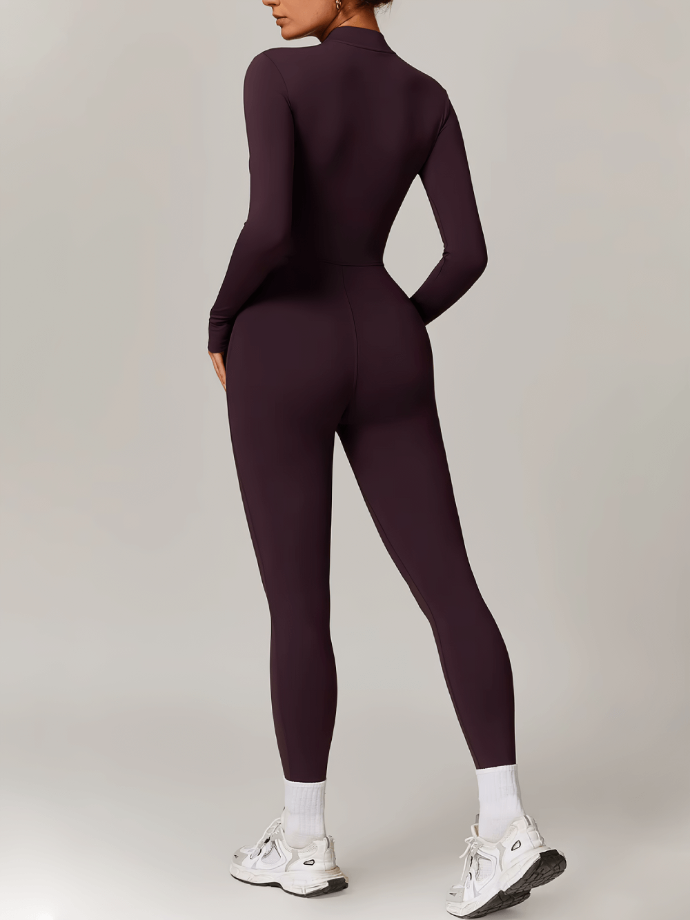 Woman wearing full-length athletic jumpsuit for yoga and fitness, showcasing sleek design in nylon and spandex for freedom of movement.