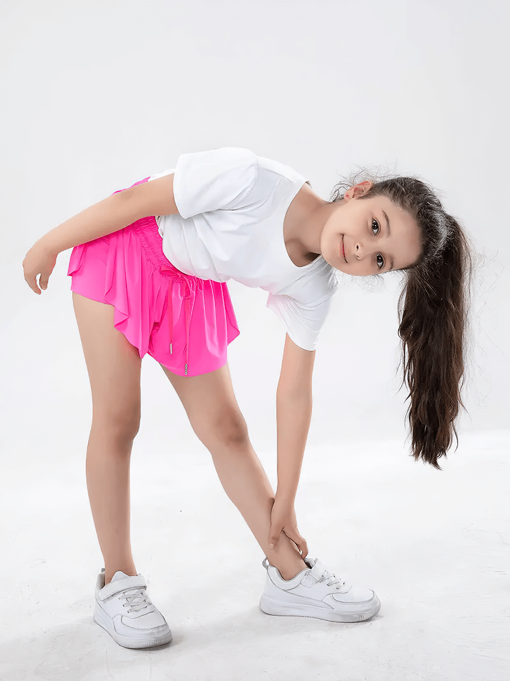 Girl wearing Girls' Bright Sports Shorts with Pleated Design - SF3829, bending while stretching, showcasing vibrant color and style.