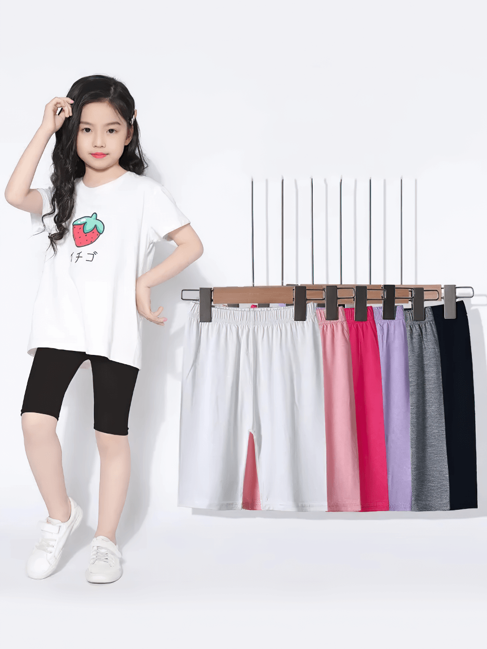 Girl modeling Girls Elastic Sport Capri Shorts for Active Play - SF3877 in black with other color options shown on hangers.