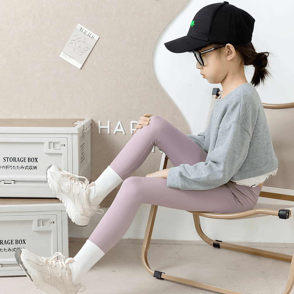 Young girl in Girls Elastic Stretch Ankle Leggings for Fitness - SF3756, sitting in a stylish room, showcasing flexibility and comfort.