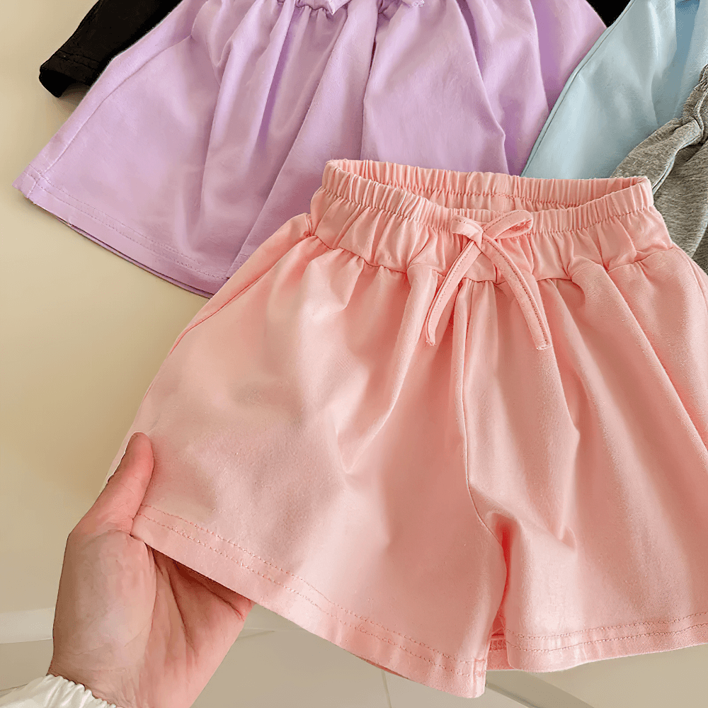Hand holding Girls' Soft Cotton Drawstring Loose Shorts - SF3737 in multiple colors on display