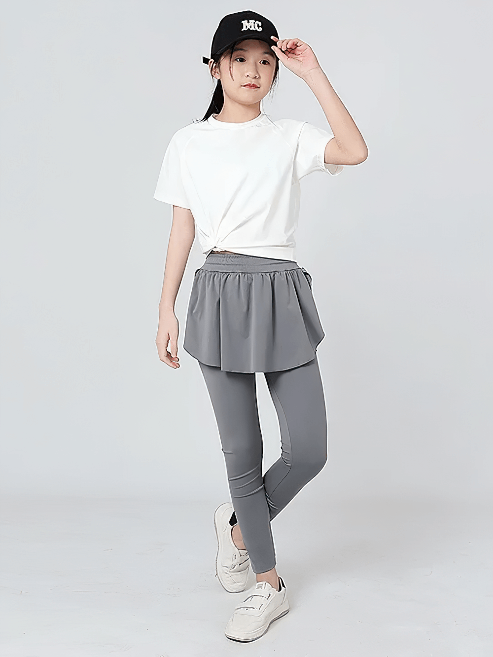 Girl in Girls Sports Leggings with Flow Skirt Design - SF3673, wearing white tee and cap, showcasing sporty and stylish outfit.