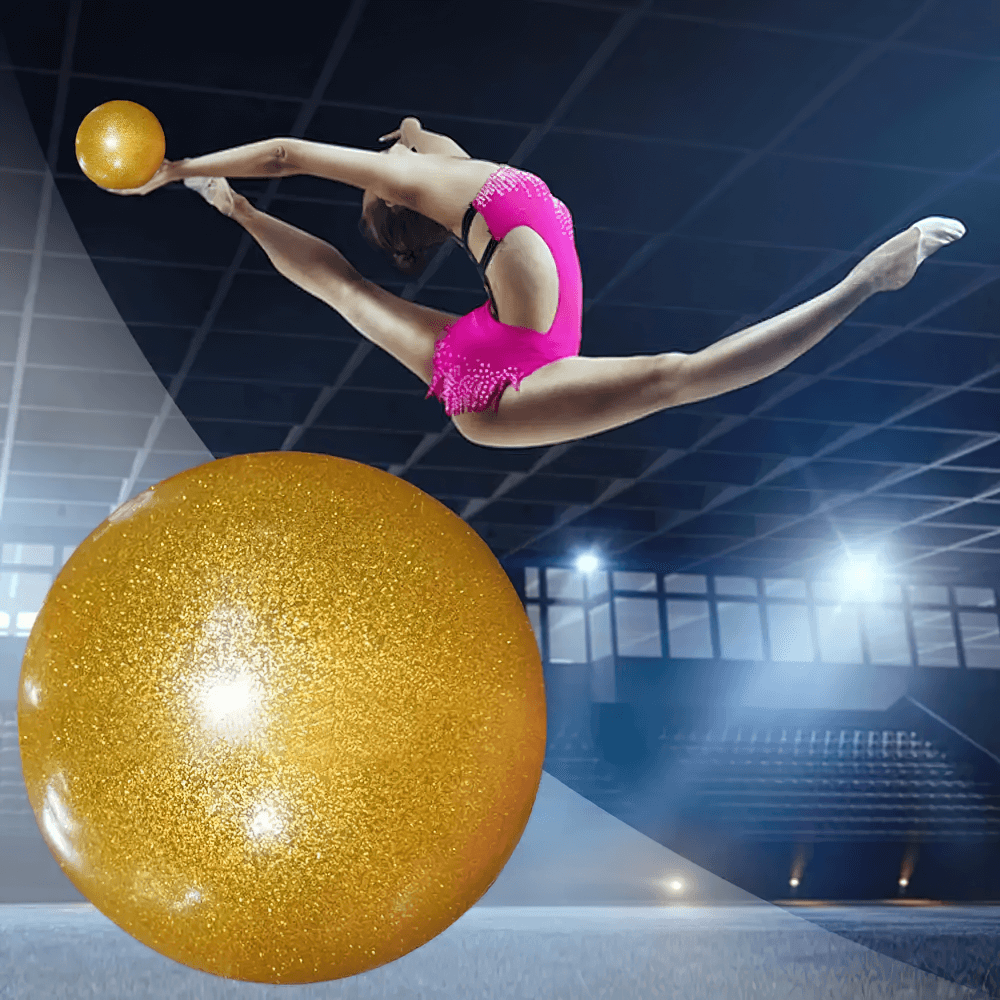 Dancer mid-leap with a gold glitter exercise ball, showcasing flexibility and balance in a dimly lit gymnasium setting.