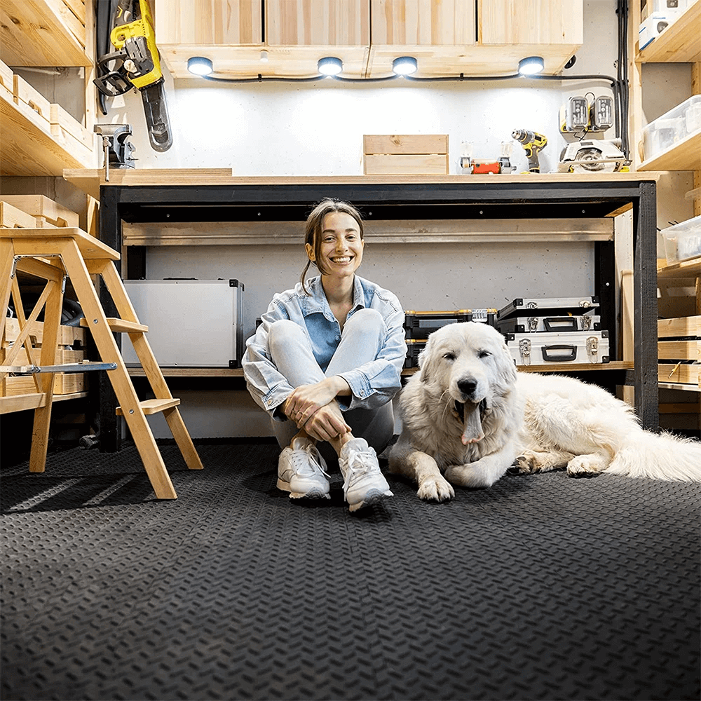 Woman sitting on interlocking EVA foam gym mats with a dog in a cozy home workshop, showcasing durable and water-resistant flooring.