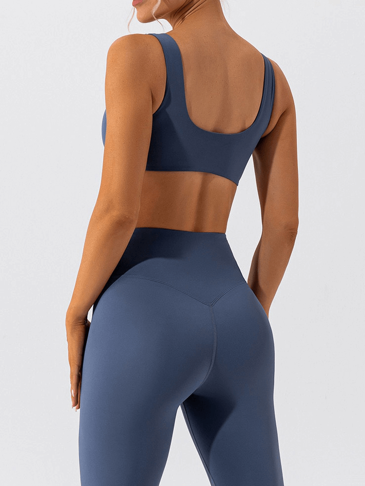 Woman wearing blue seamless sports bra and leggings for gym workout.