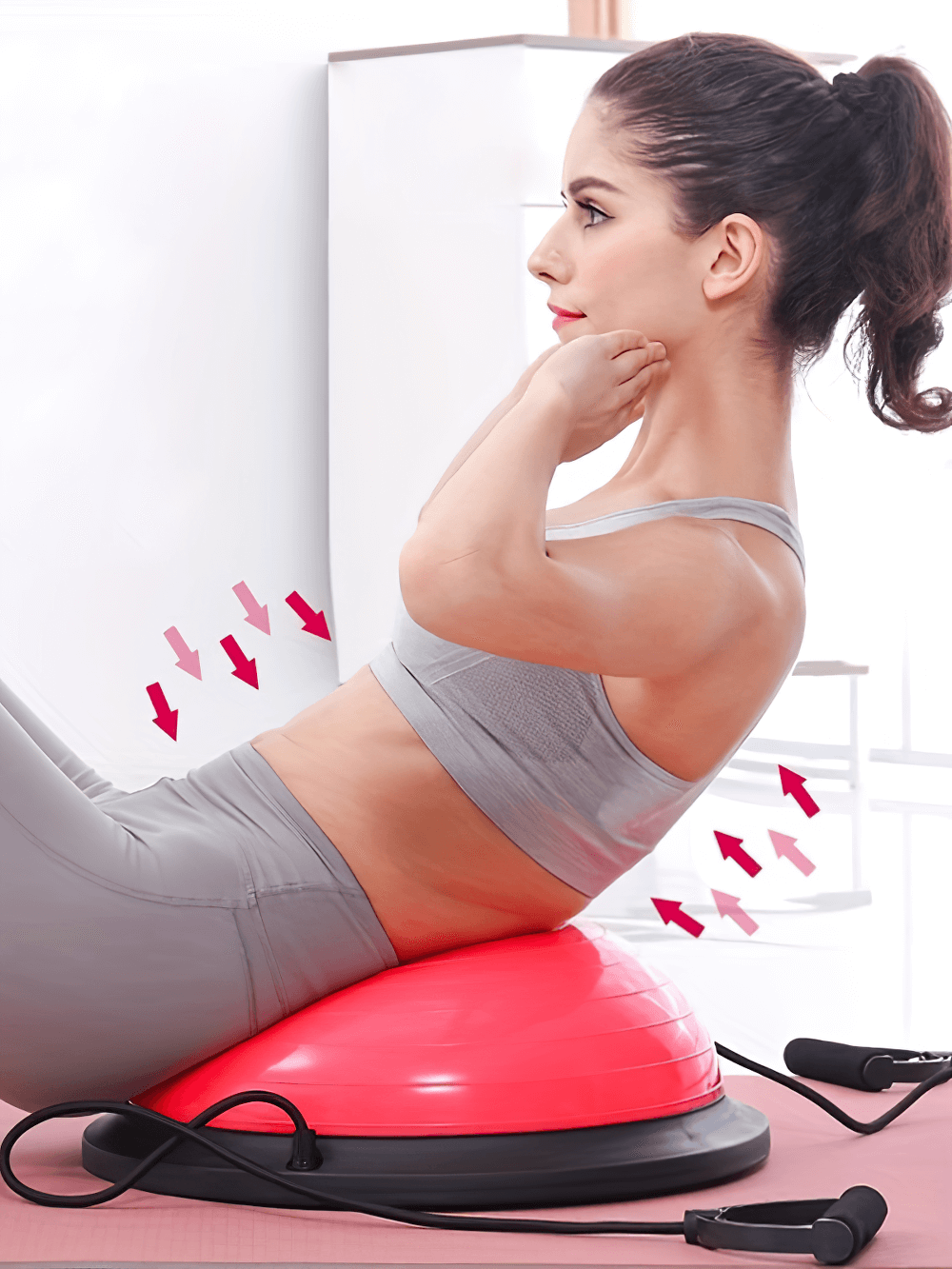 Woman doing sit-ups on half balance trainer ball with resistance bands for core strength and stability training.