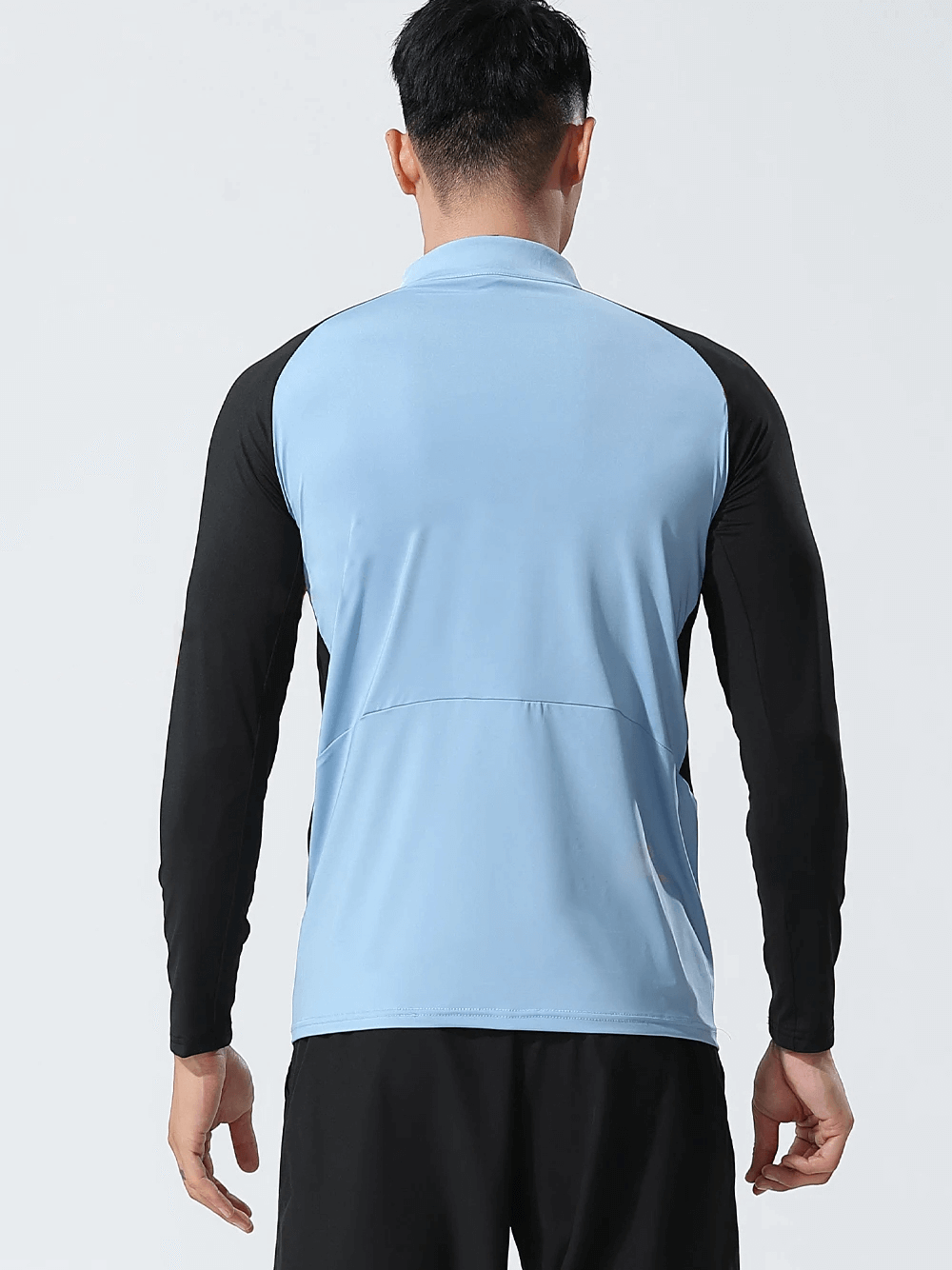 Back view of a man wearing a blue and black half-zip athletic fit training top, designed for sweat-wicking performance. Perfect for workouts.