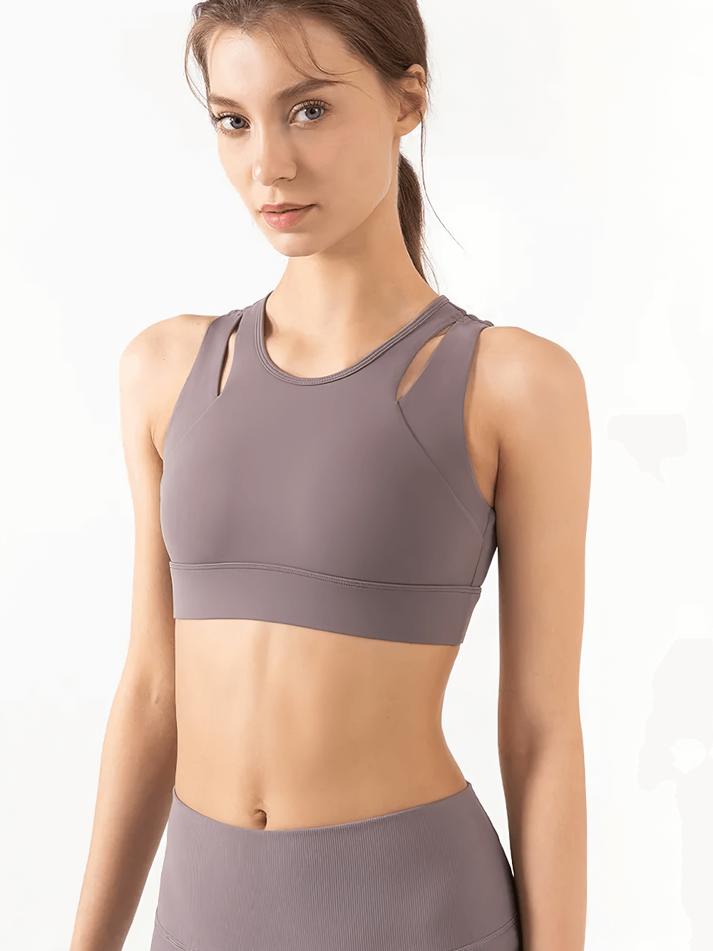 Woman wearing high-impact sports bra in grey with cut-out design, ideal for yoga and gym. Breathable, quick-dry fabric for performance.
